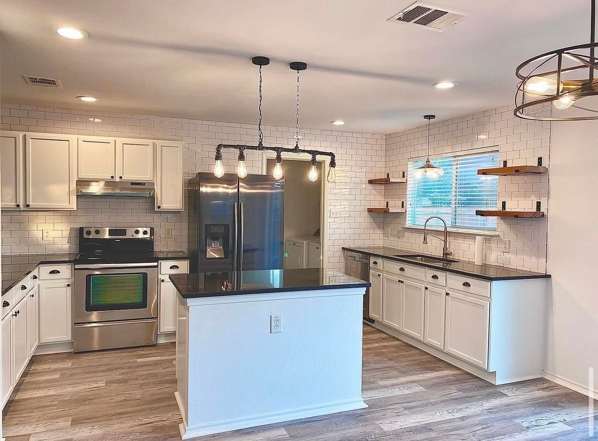 A kitchen with white cabinets , stainless steel appliances , and a large island.