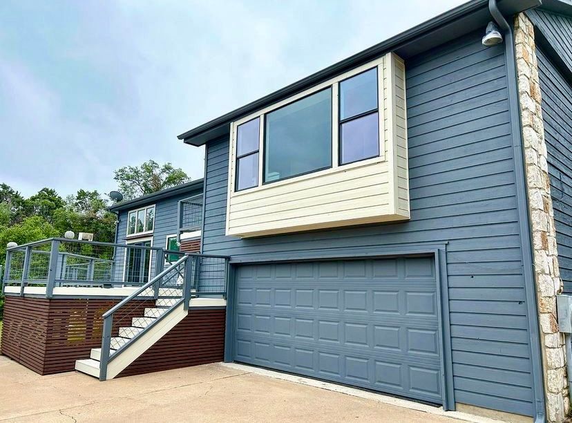 Blue house exterior with garage, beige bay window, and front deck with stairs