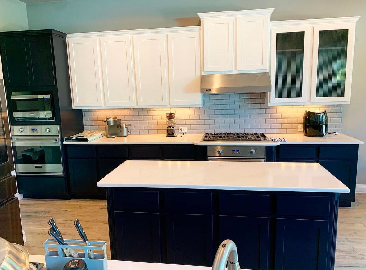 Navy and white kitchen with stainless steel appliances, subway tile backsplash, and a white countertop island.