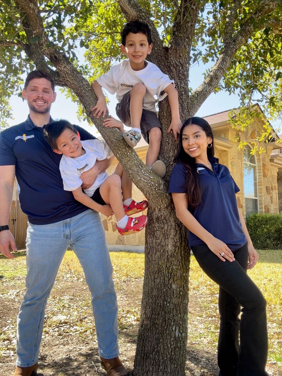 A family is posing for a picture in front of a tree.