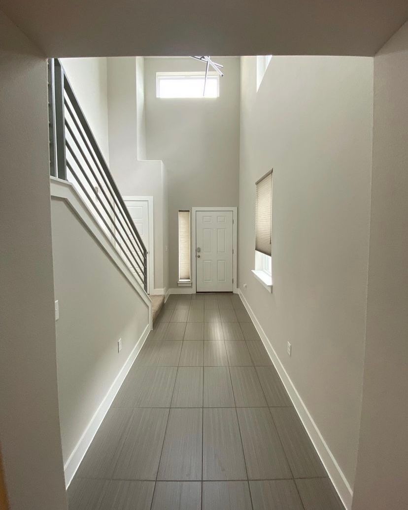 A long hallway with a staircase and a door
