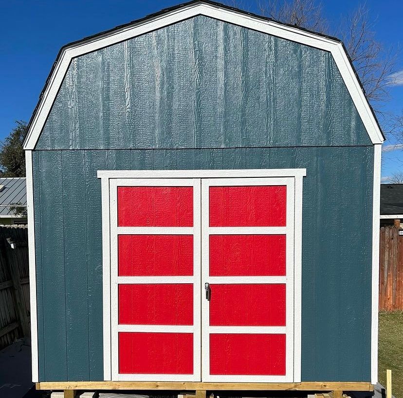 A blue barn with red doors and windows.