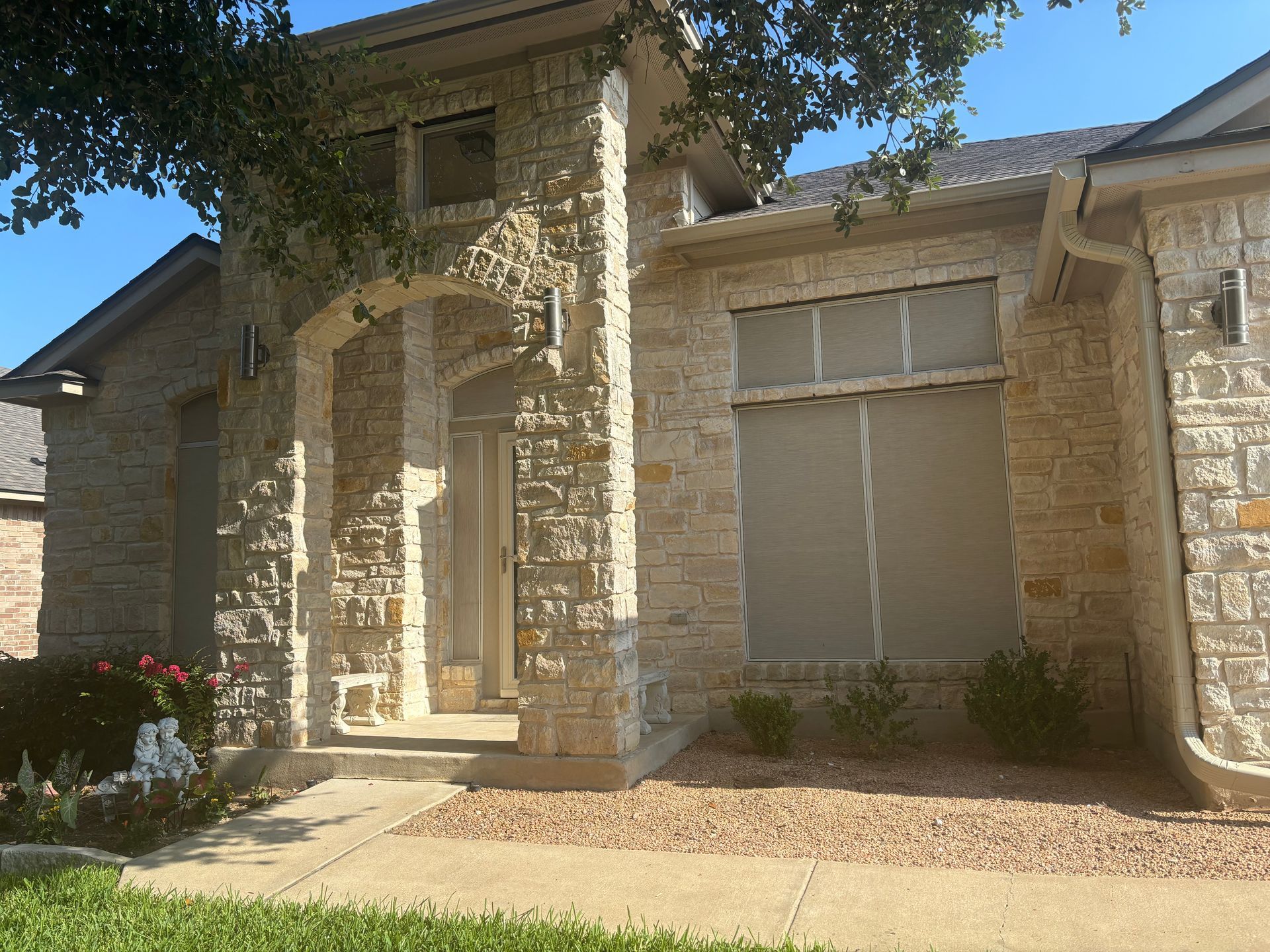 A house with a stone facade and a tree in front of it