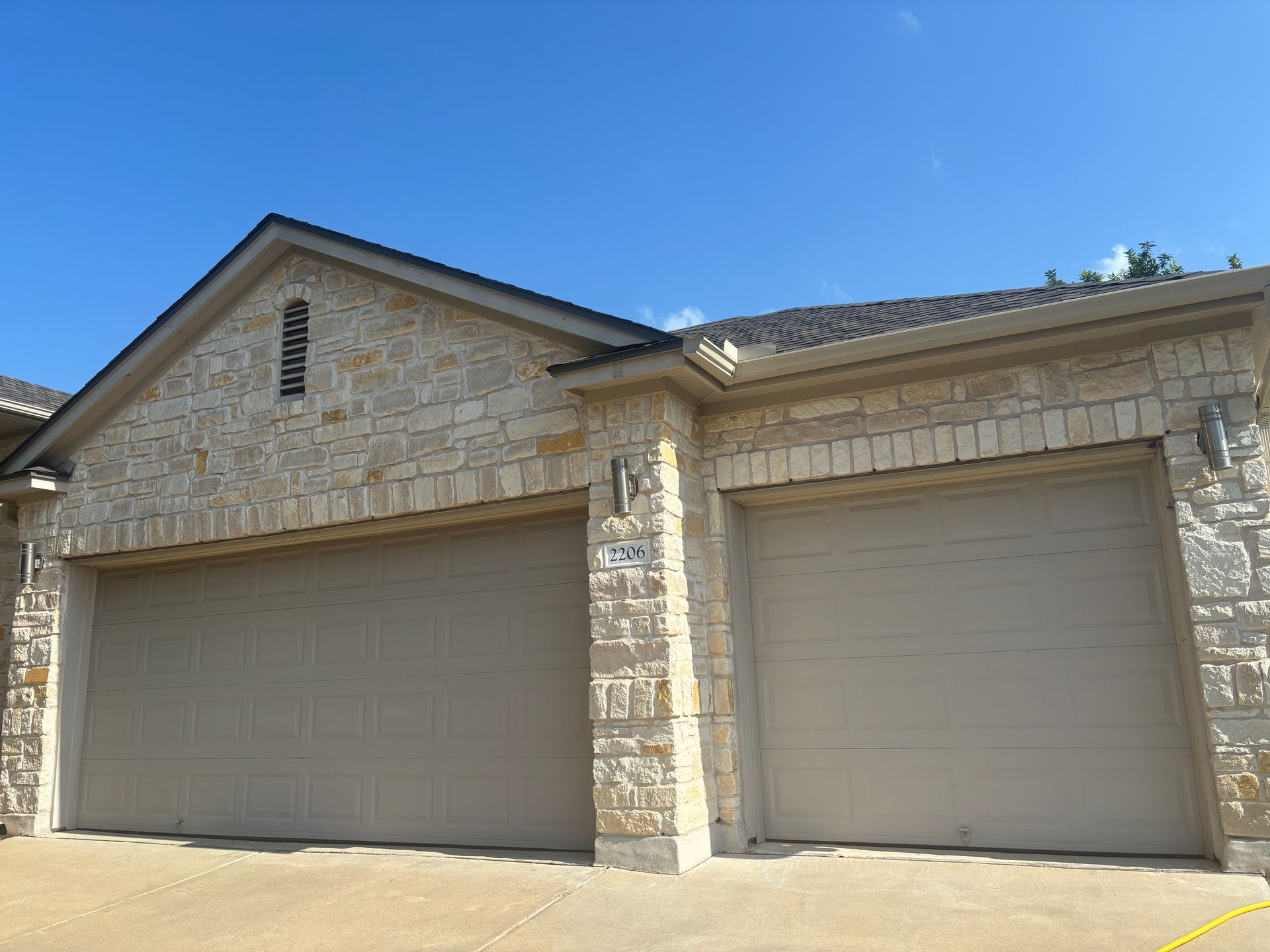 There are two garage doors on the side of a house.