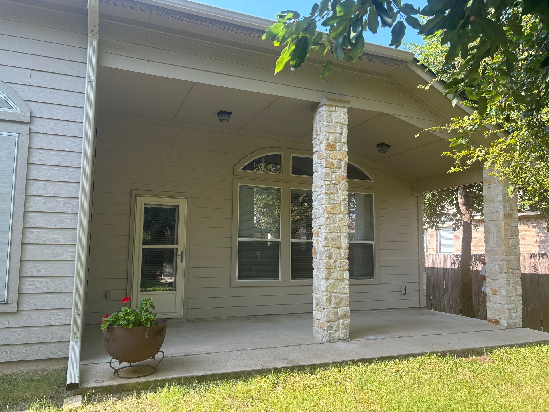 A white house with a covered porch and a potted plant in front of it.