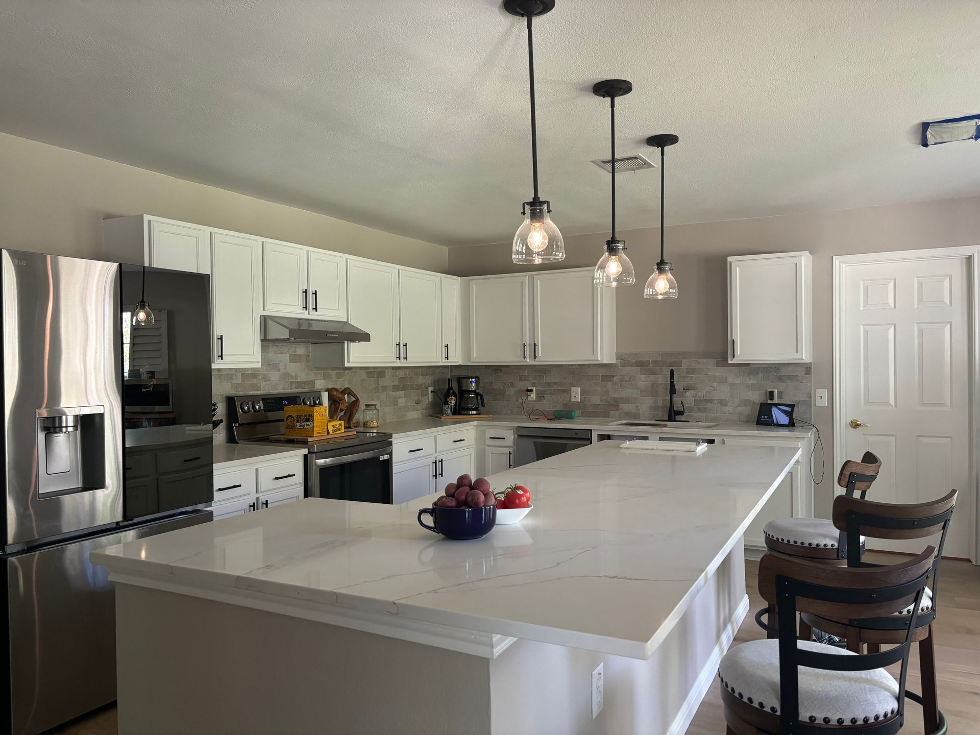 A kitchen with white cabinets , stainless steel appliances and a large island.