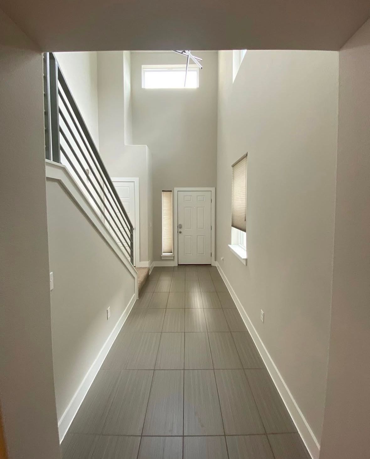 A long hallway with a staircase and a door