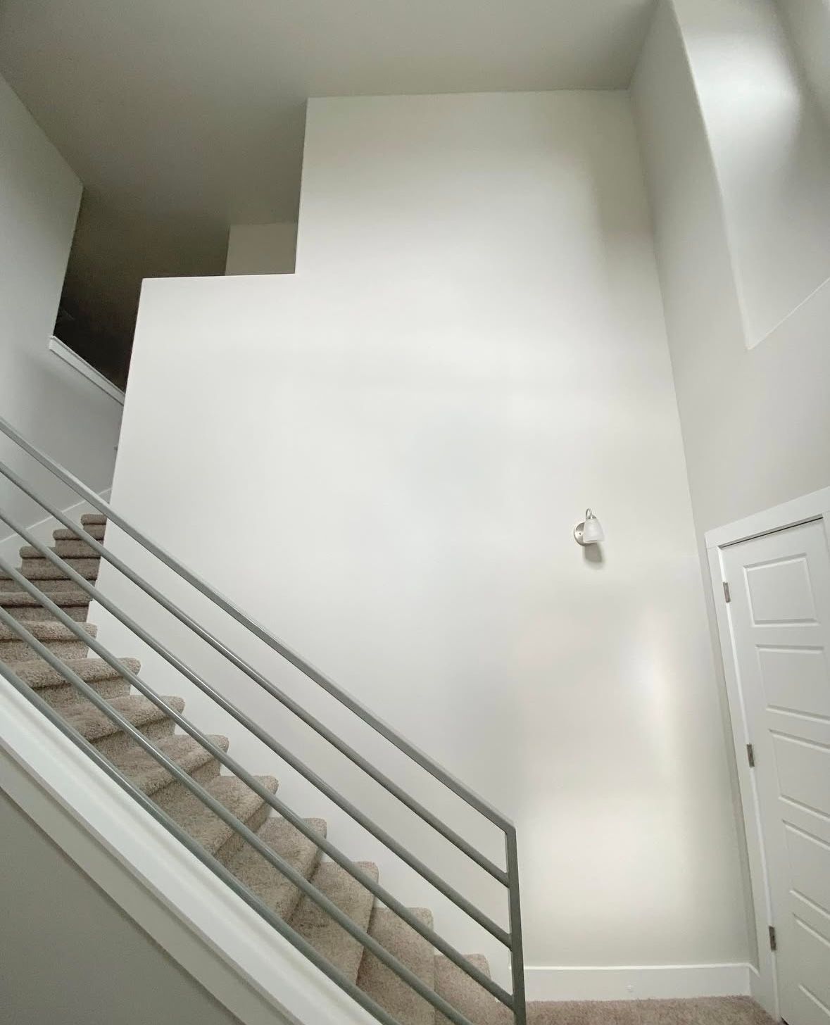 A staircase with a metal railing and a white wall