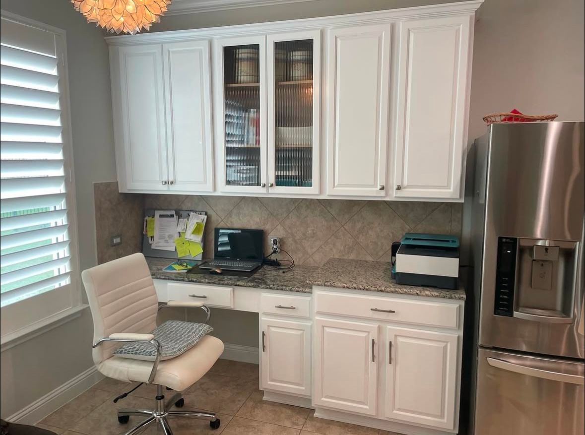 A kitchen with white cabinets and a stainless steel refrigerator.
