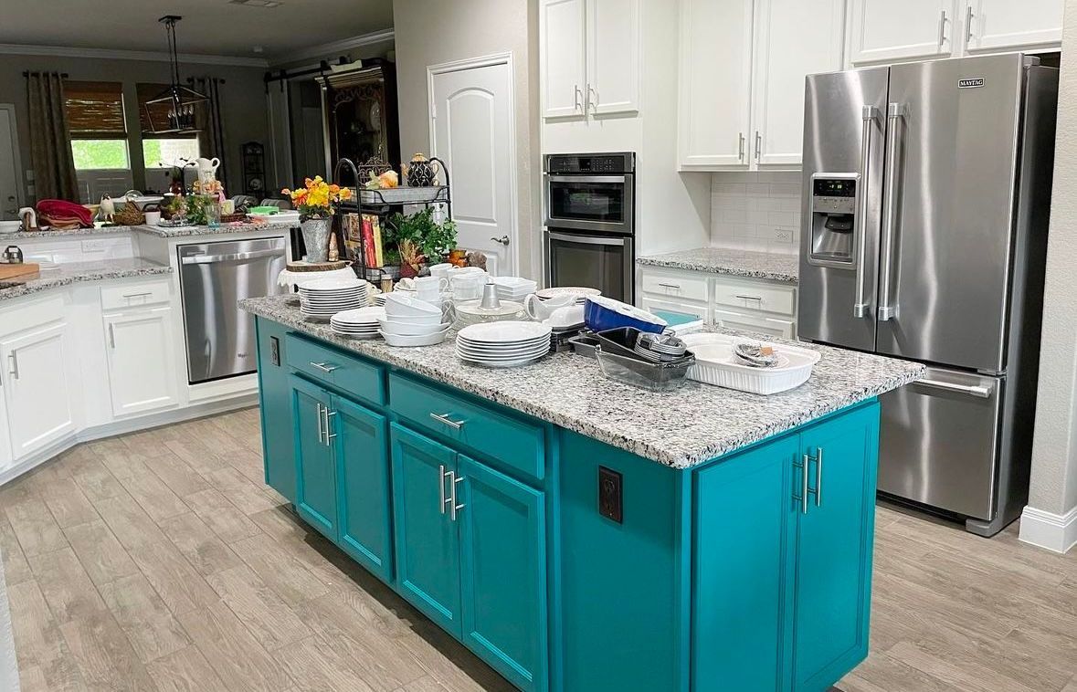 A kitchen with blue cabinets , granite counter tops , stainless steel appliances and a large island.