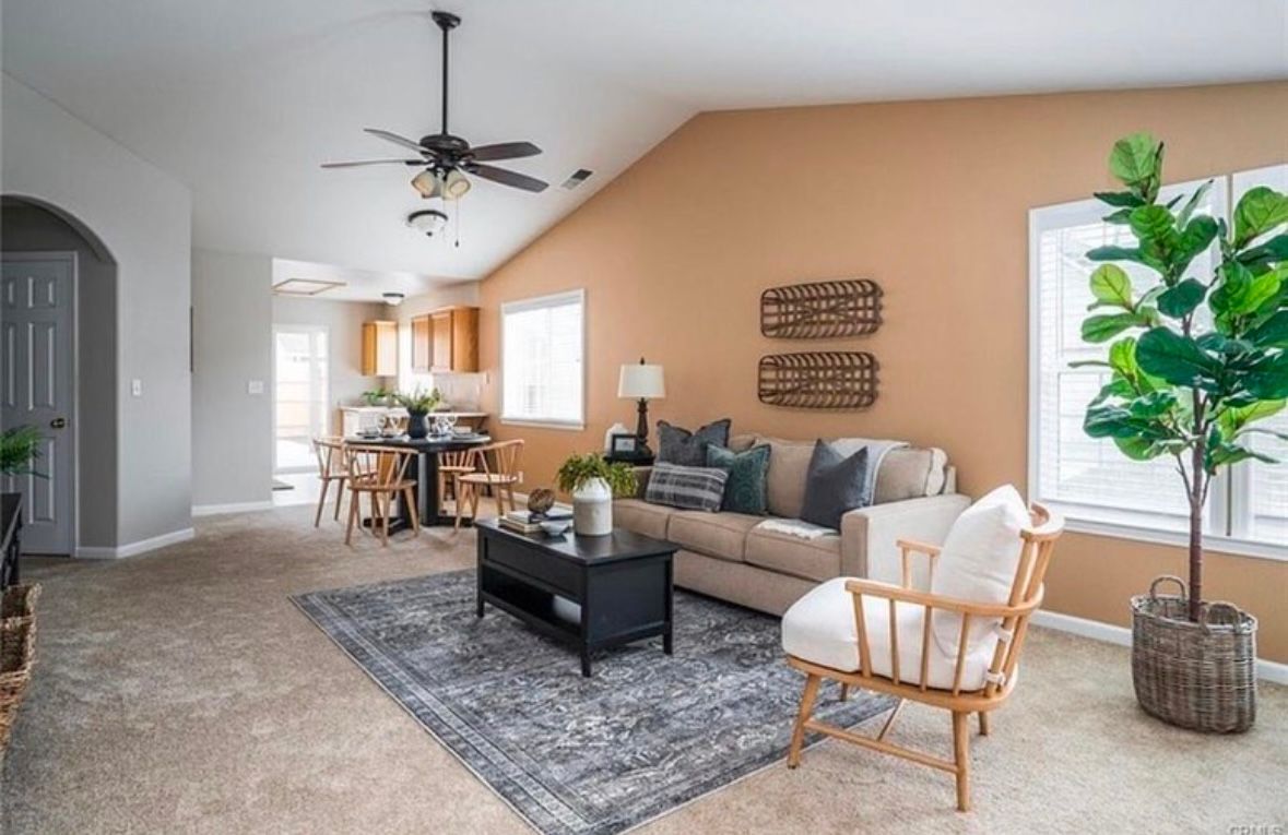 A living room with a couch , chair , coffee table and ceiling fan.