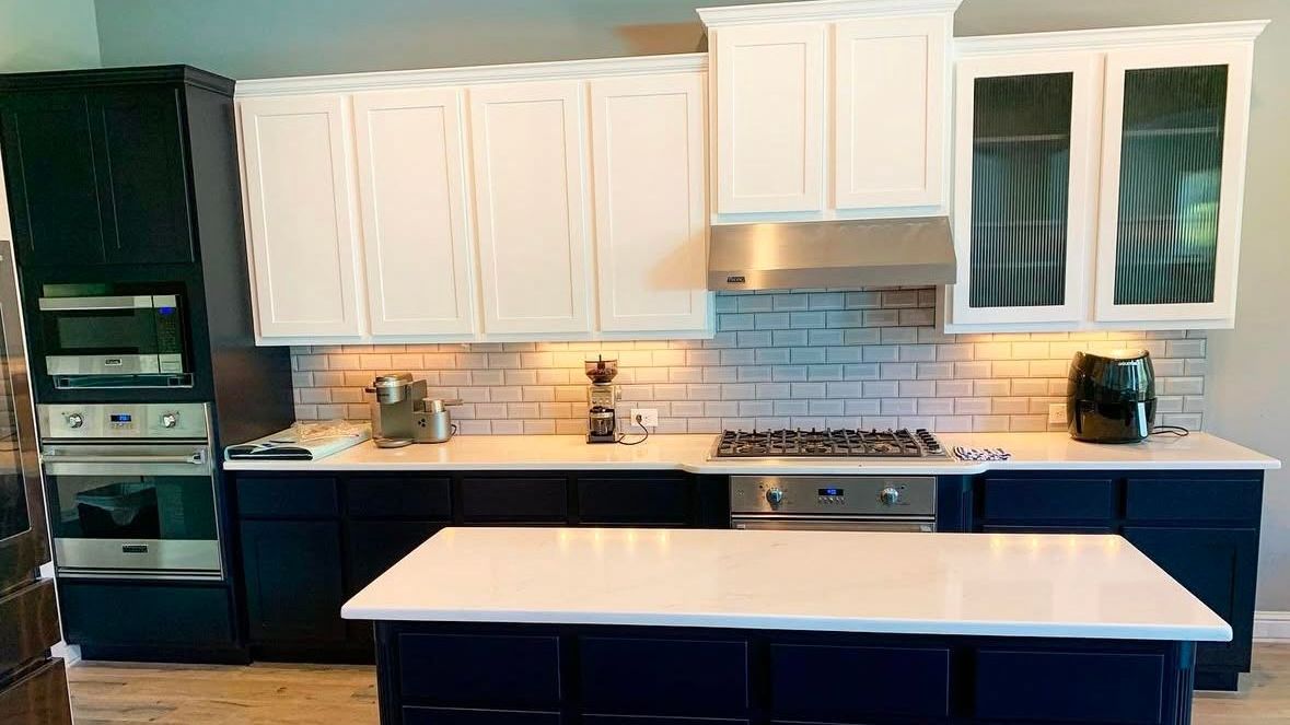 A kitchen with blue cabinets and white counter tops and a large island.