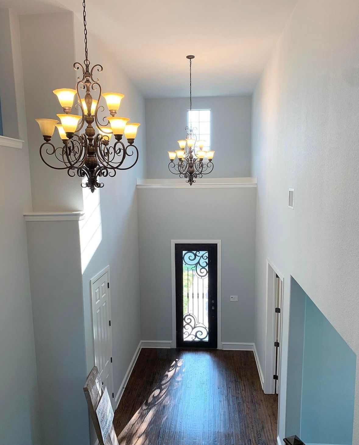 A hallway with two chandeliers hanging from the ceiling