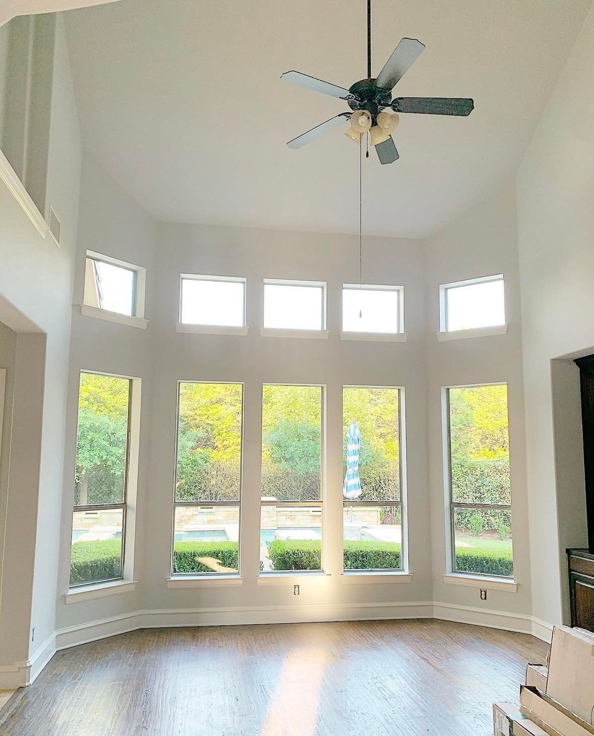 A living room with a lot of windows and a ceiling fan.