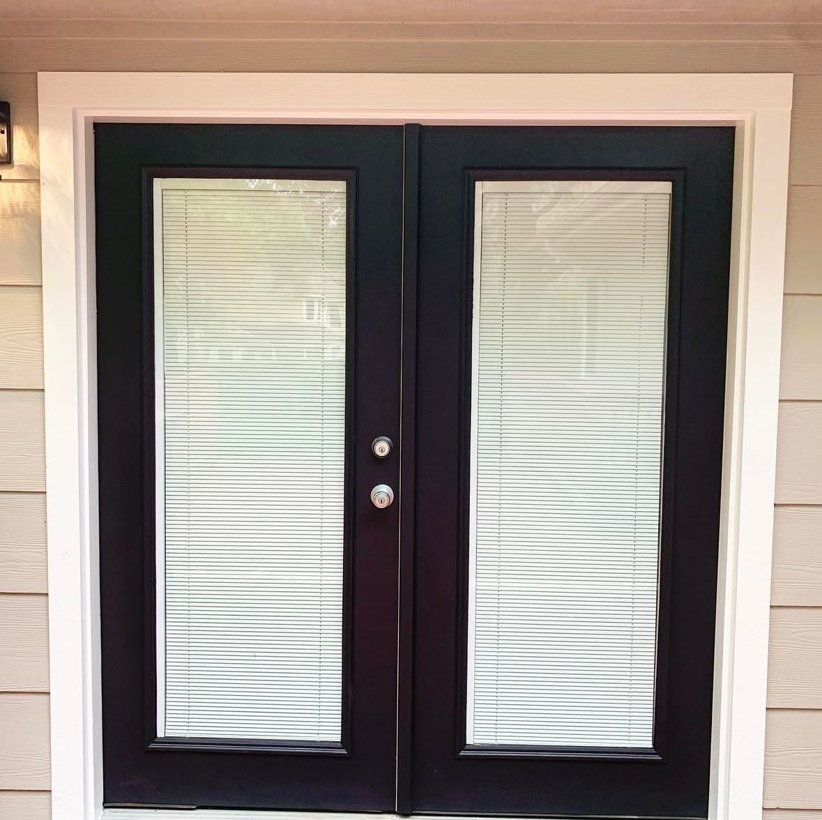 A black door with blinds on it is on a house.