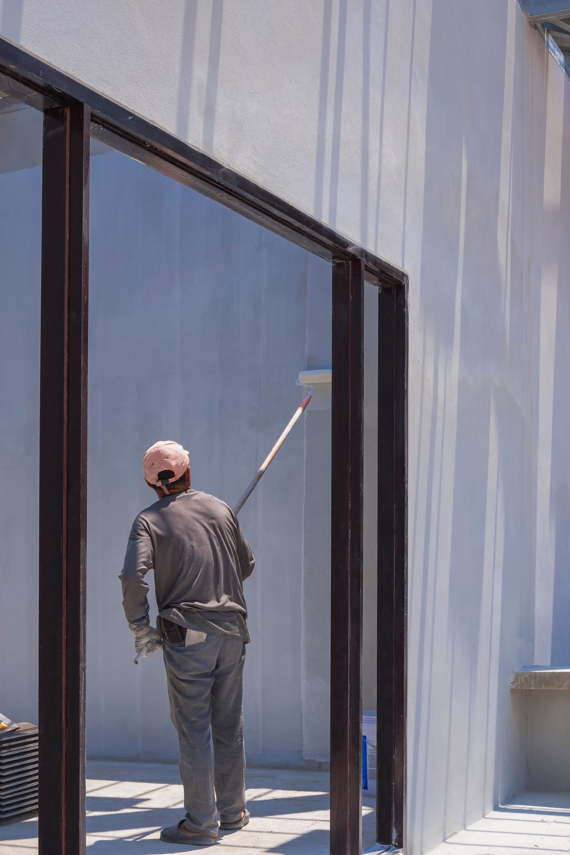 A man is painting a wall with a roller.