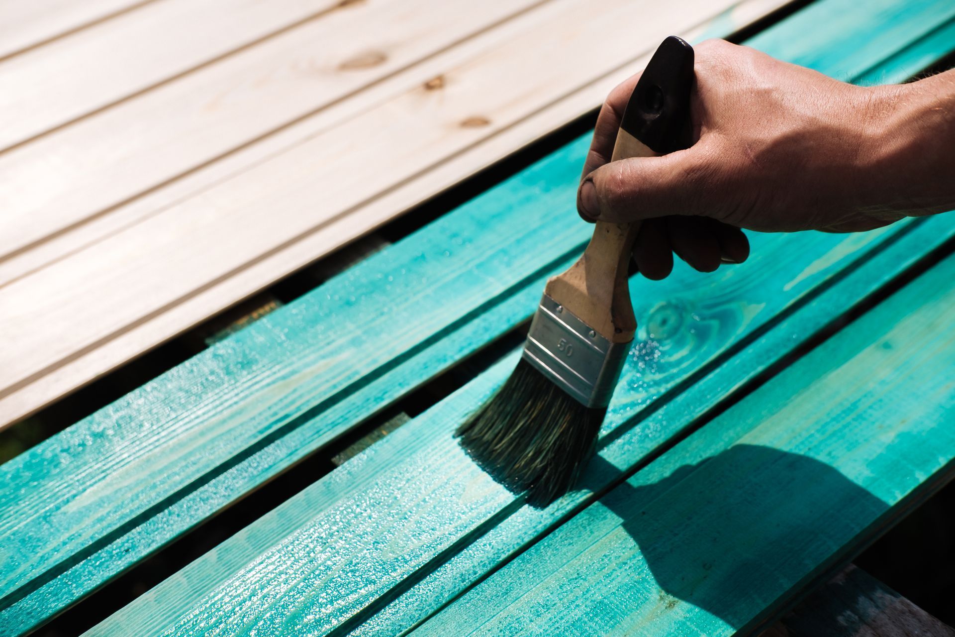 A person is painting a wooden surface with a brush.