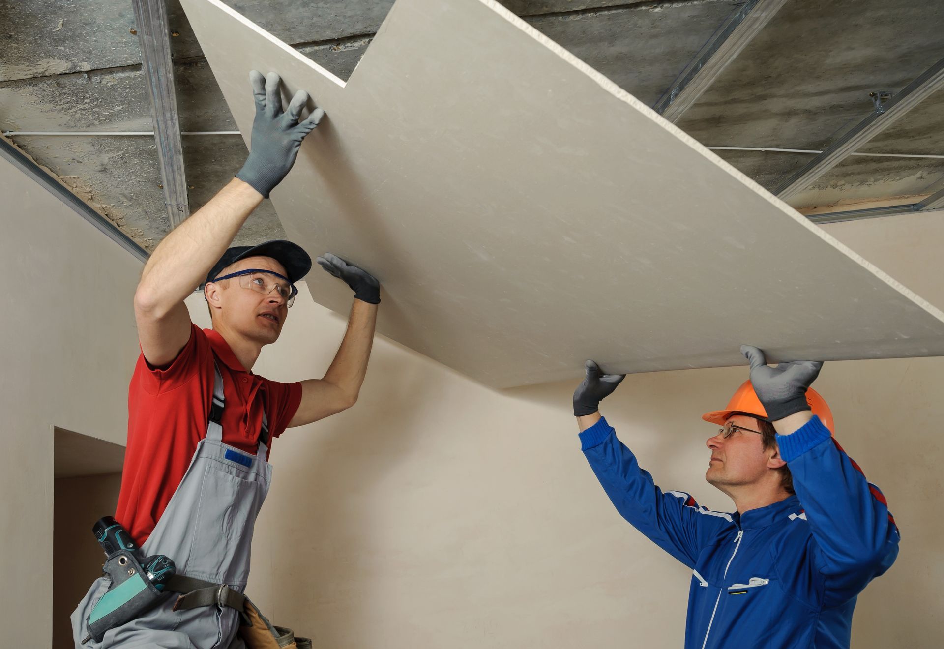 Two men are working on a ceiling in a room.