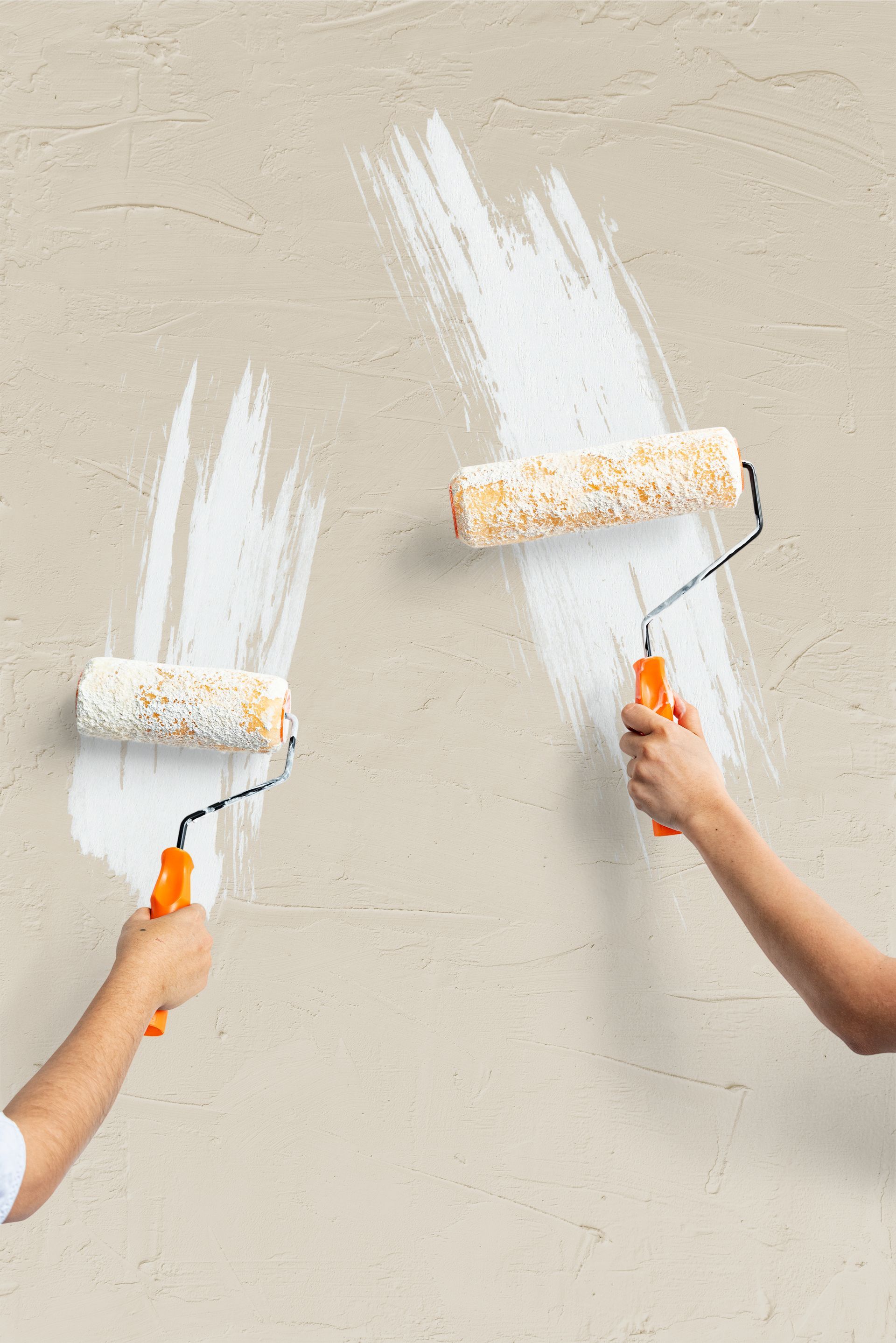Two people are painting a wall with paint rollers.