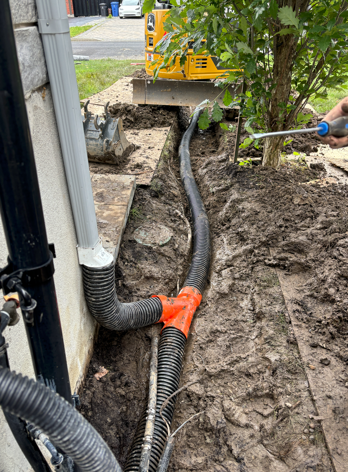 Une personne tient un tournevis à côté d'un tuyau dans la terre.