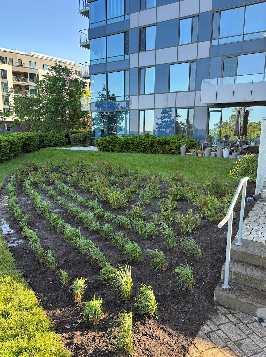 Un grand bâtiment avec beaucoup de fenêtres et un jardin devant.