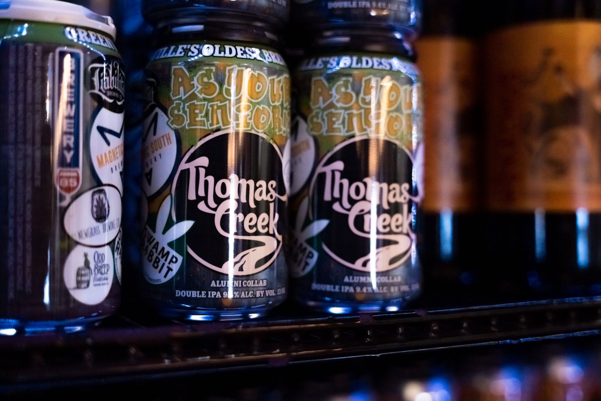 three cans of thomas creek beer are sitting on a shelf .