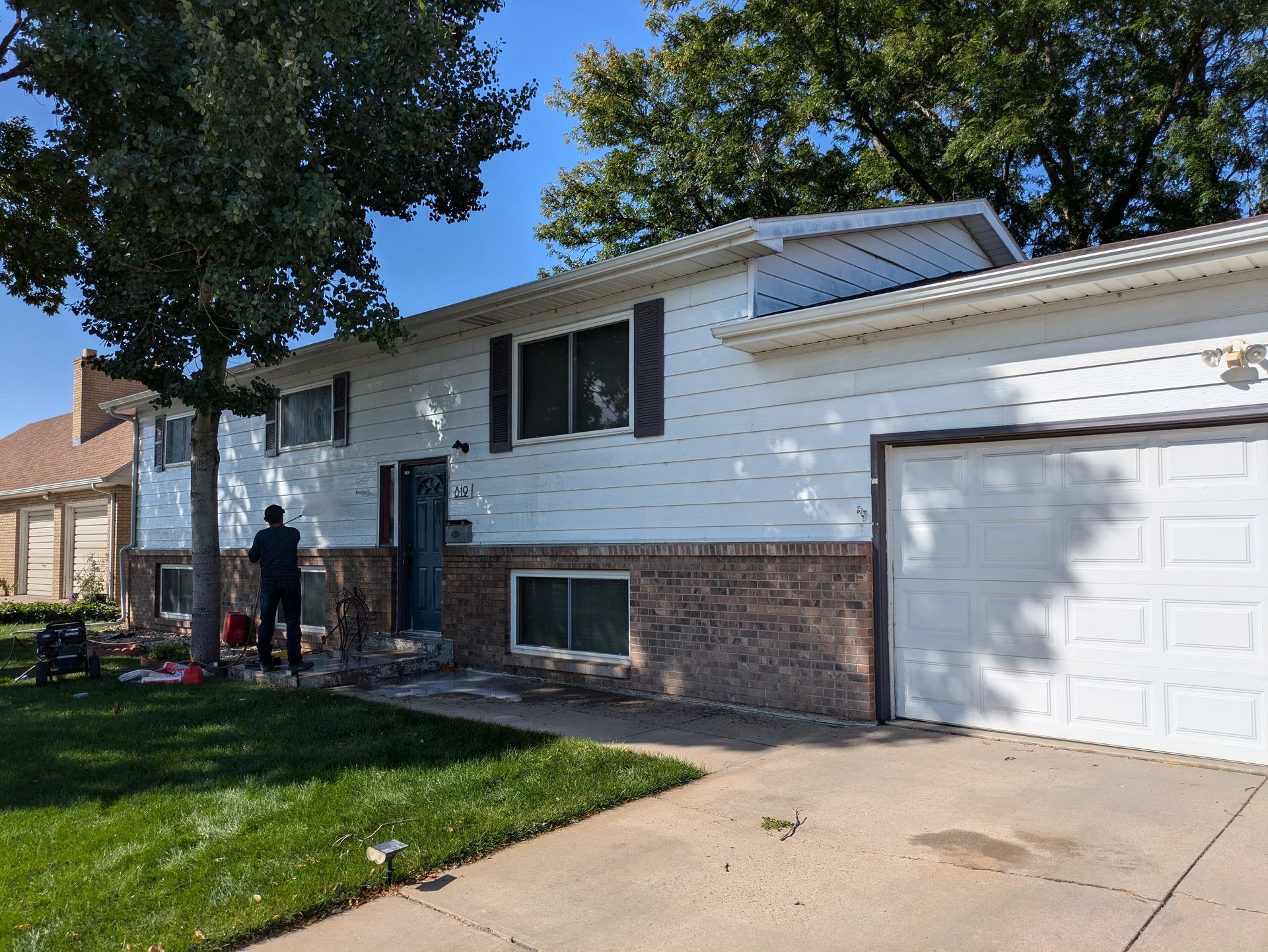 A man is standing in front of a house with a white garage door.
