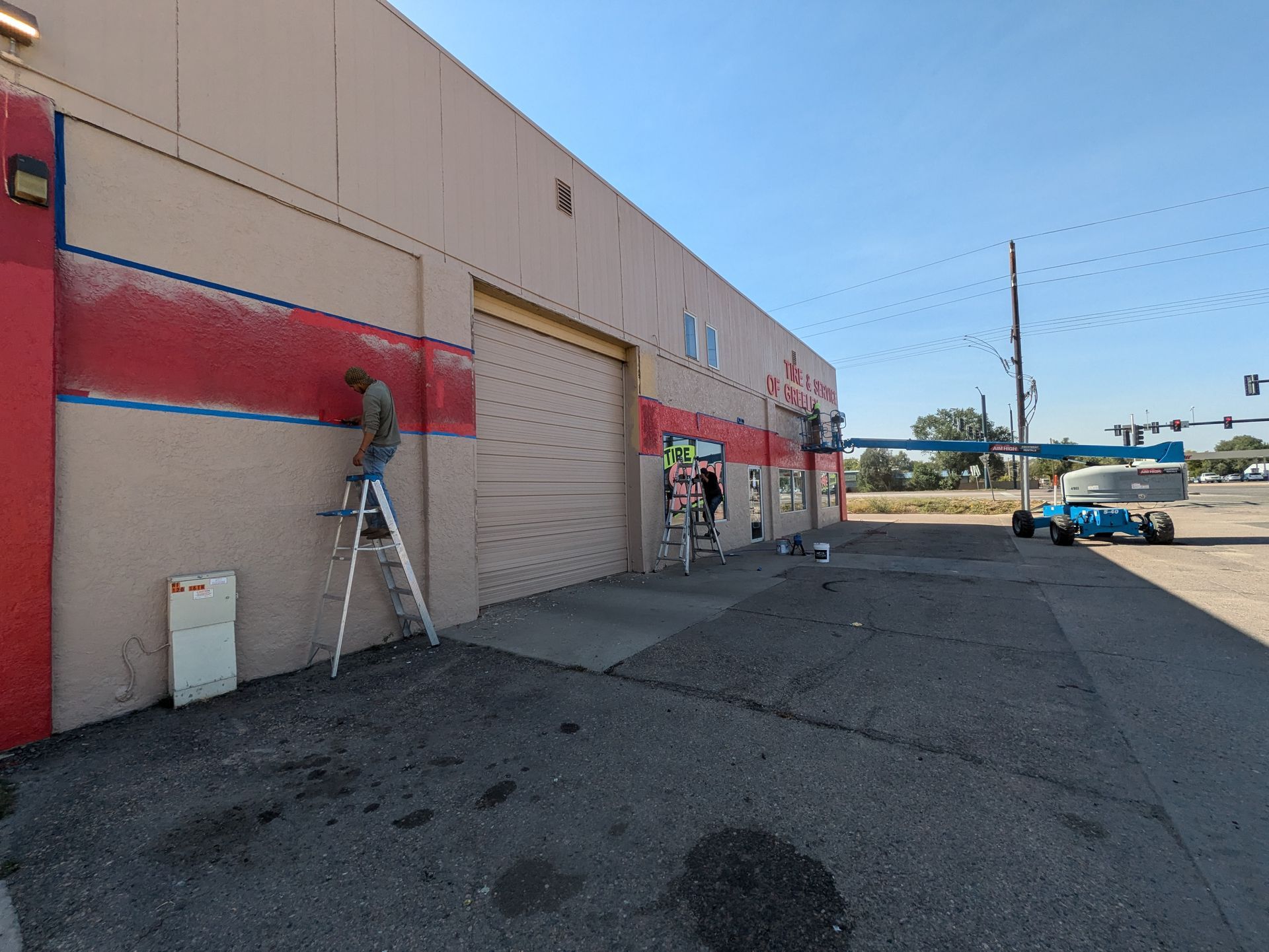 A man on a ladder is painting the side of a building.