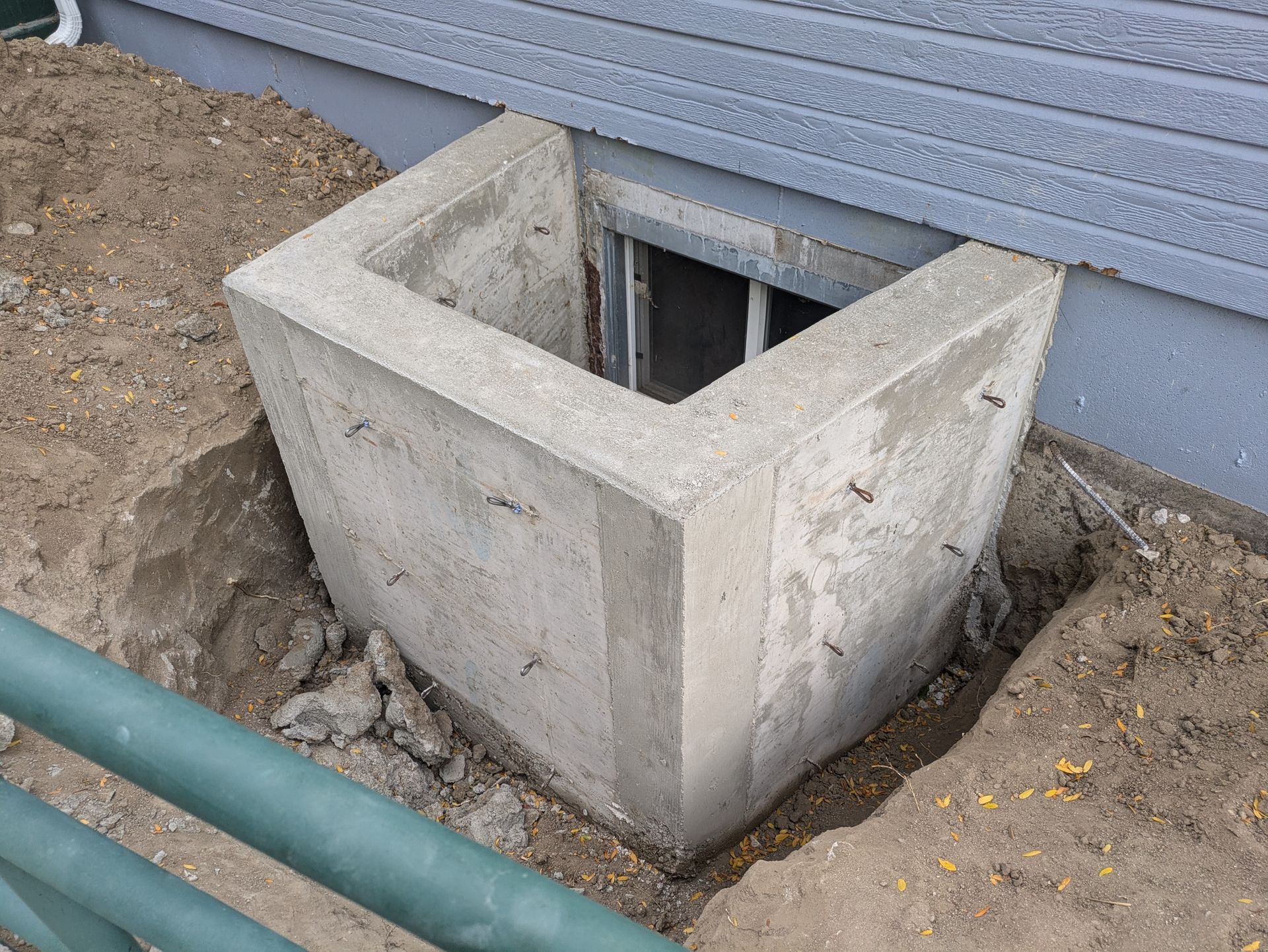 A concrete block is sitting in the dirt next to a window.