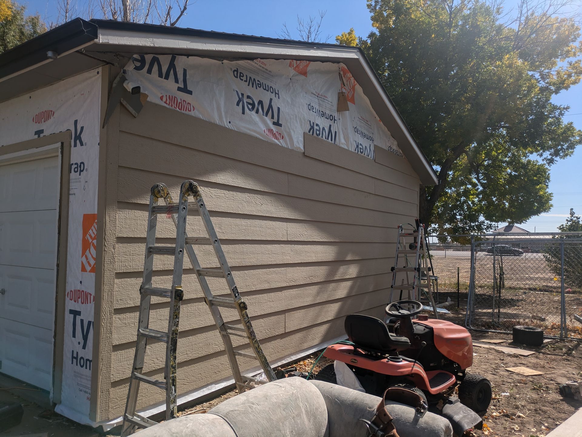 A lawn mower is parked in front of a garage under construction.