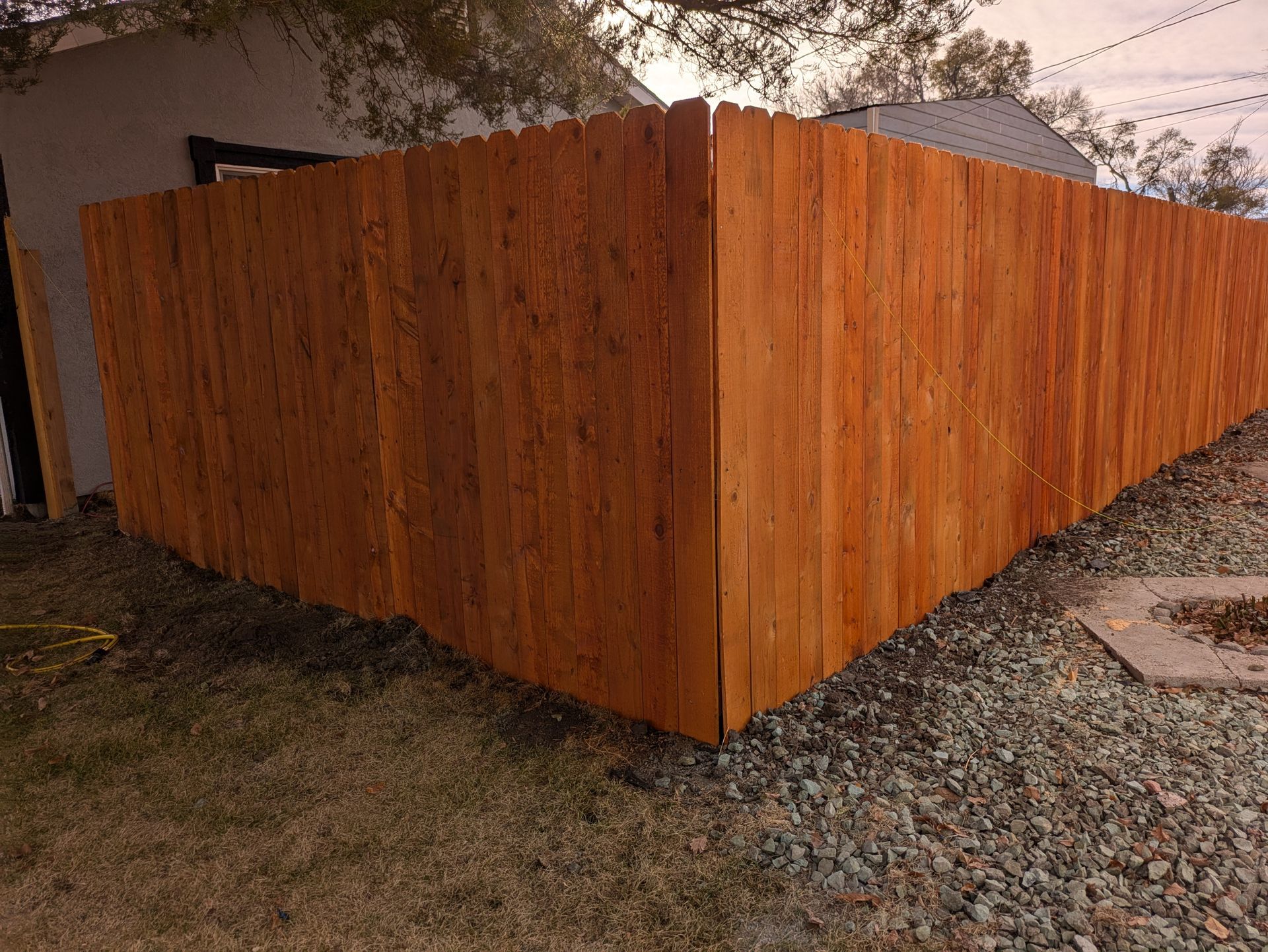 A wooden fence is in the backyard of a house.