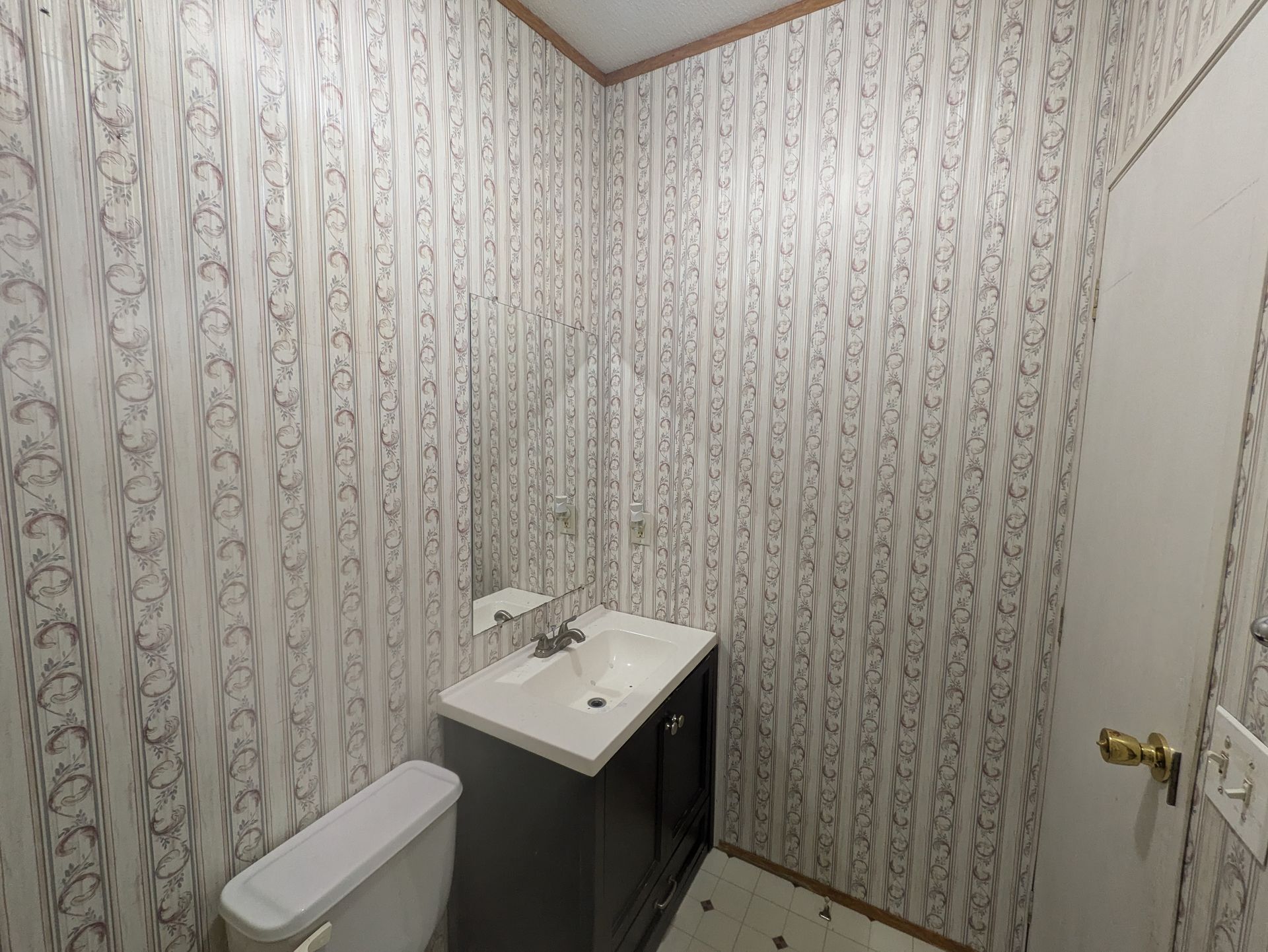 A bathroom with a toilet , sink and mirror.