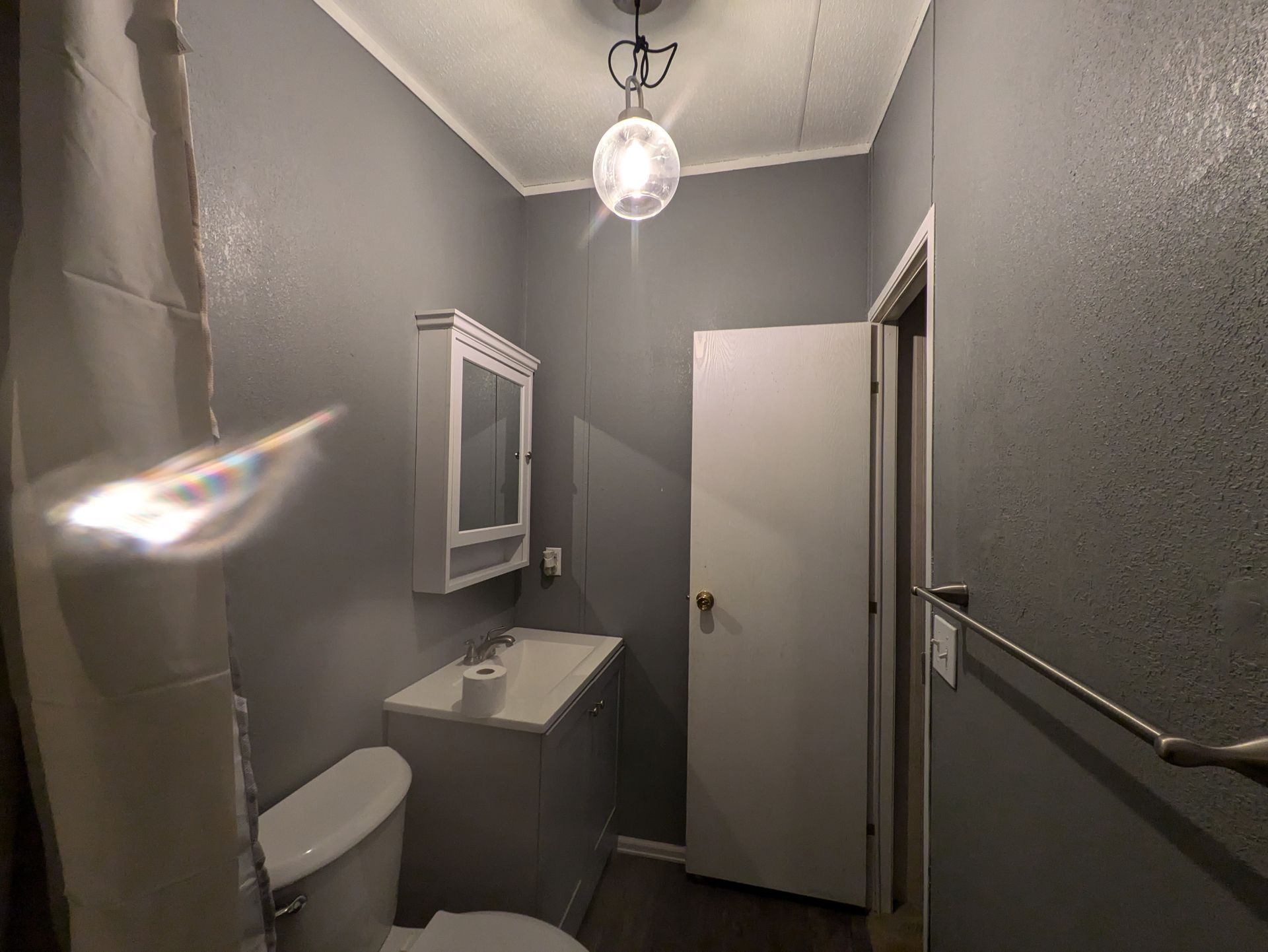 A bathroom with a toilet , sink and mirror.