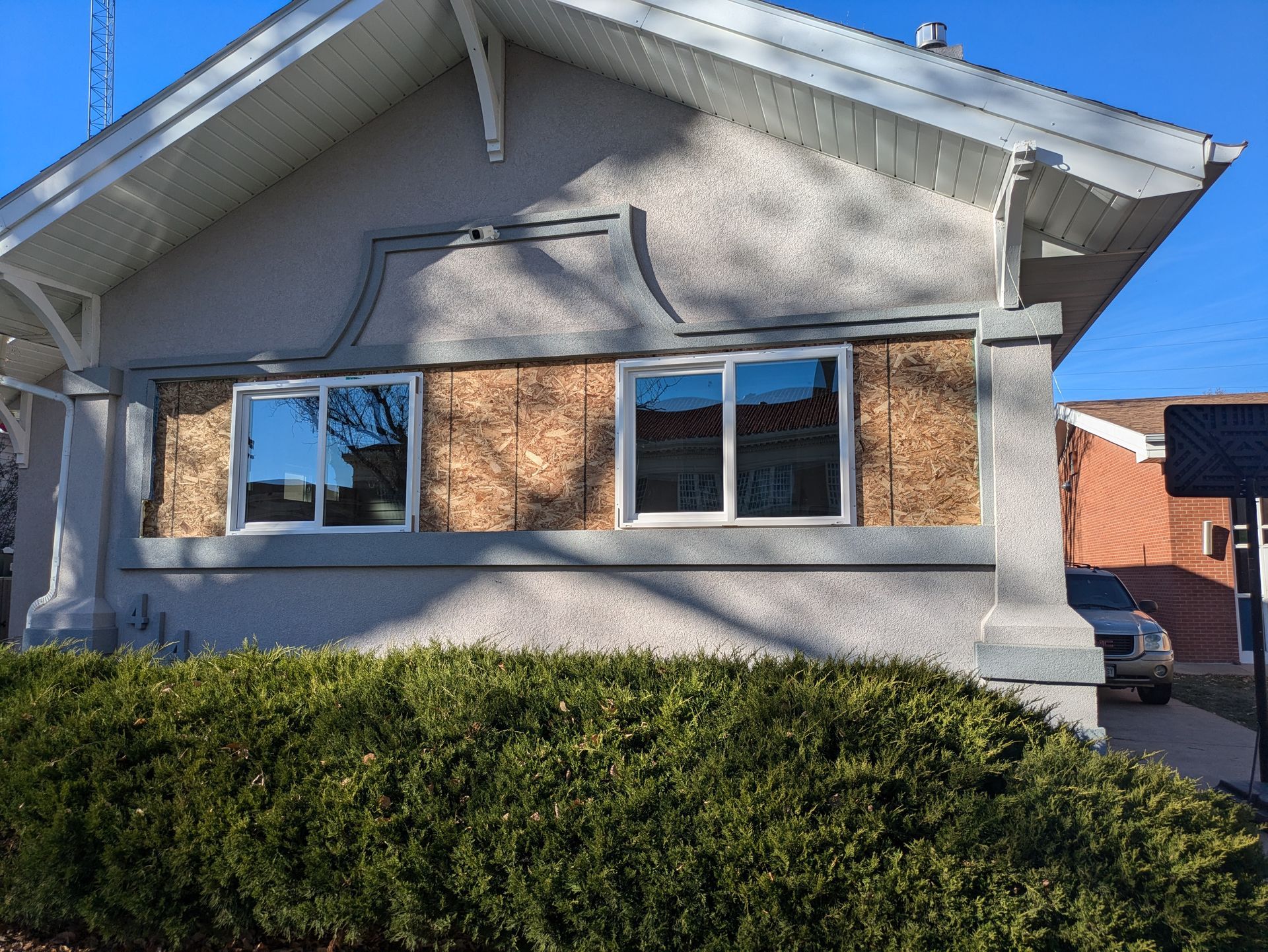 A house with a lot of windows and a hedge in front of it