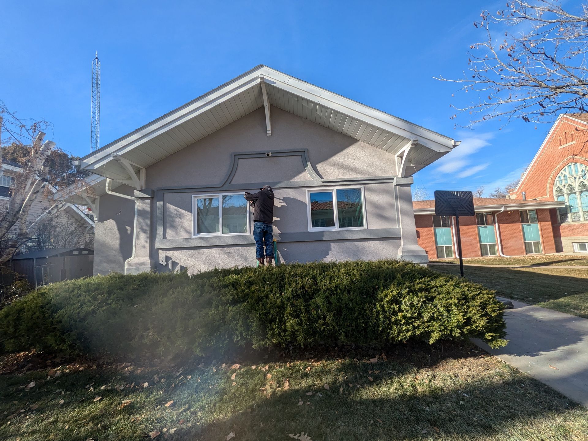 A man is standing in front of a house painting it.