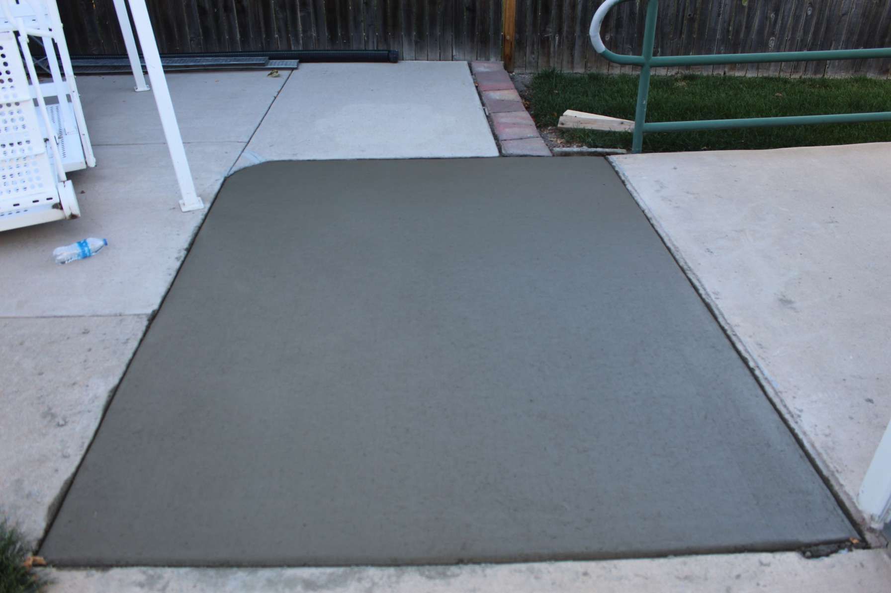 A concrete walkway is being built next to a fence
