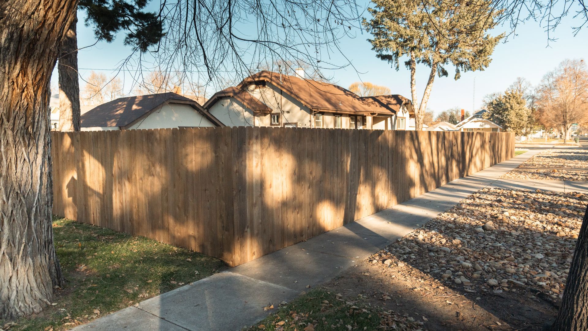 A wooden fence along a sidewalk in front of a house.