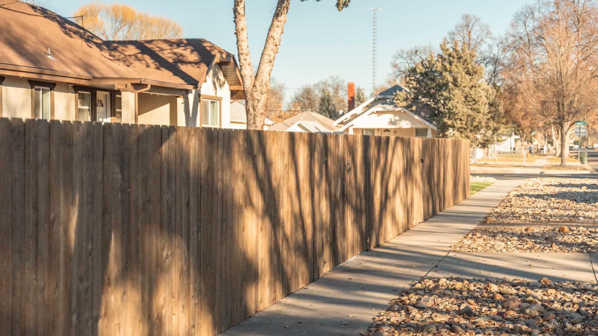 A wooden fence along a sidewalk next to a house.