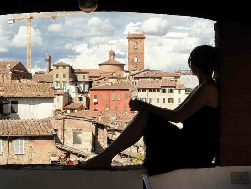 profilo di una donna seduta su un balcone che ammira Siena