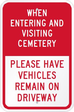 A red sign that says `` when entering and visiting cemetery please have vehicles remain on driveway ''.