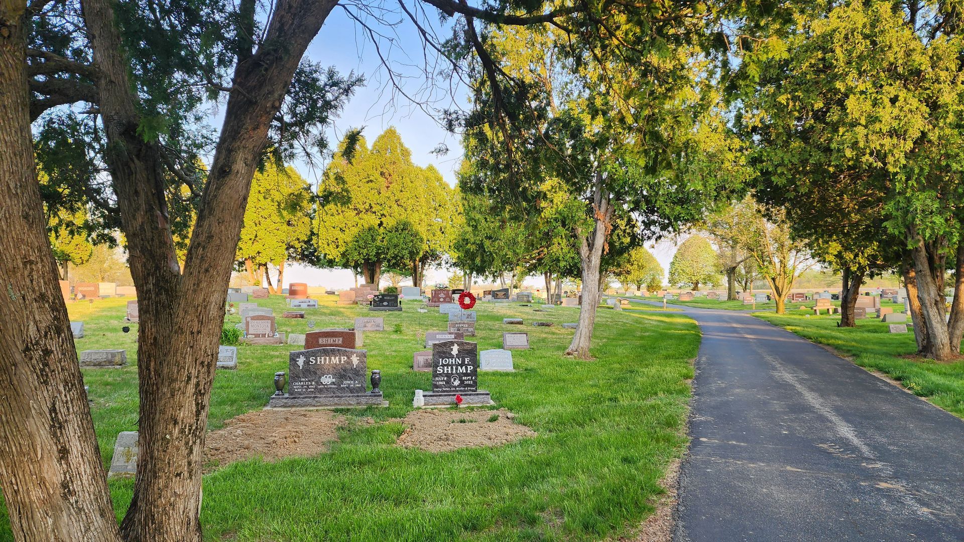 A path leading to a cemetery surrounded by trees and grass.