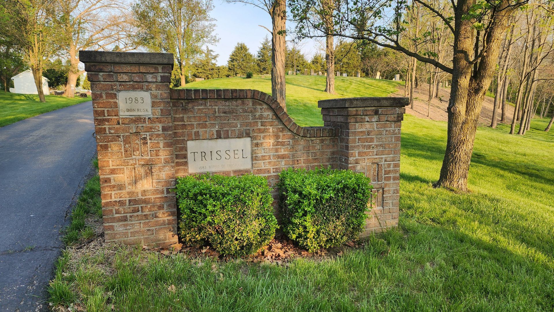 A brick wall with a sign on it that says Trissel Cemetery.