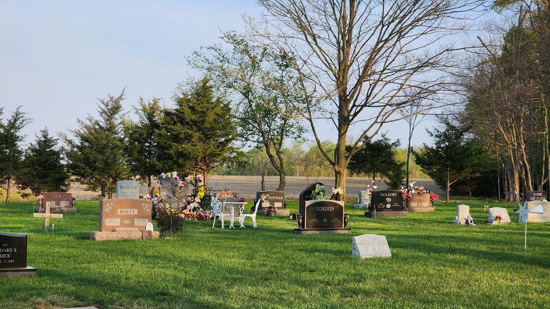 A cemetery filled with graves and trees on a sunny day.