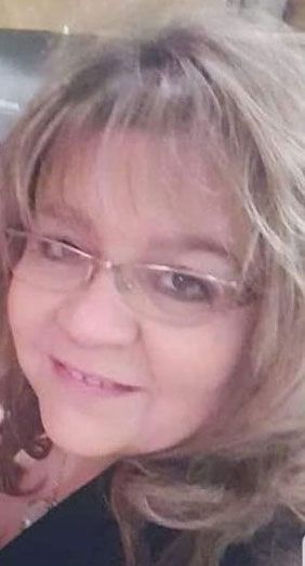 A close up of a woman wearing glasses and smiling.