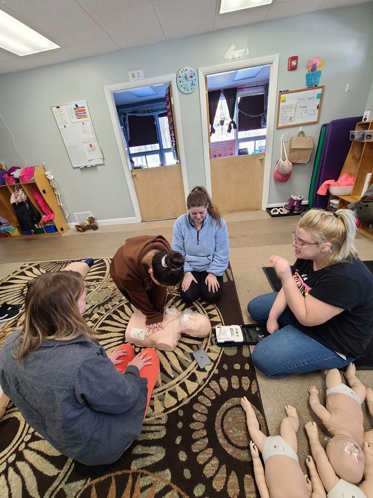A group of people are sitting on the floor in a room with dolls.