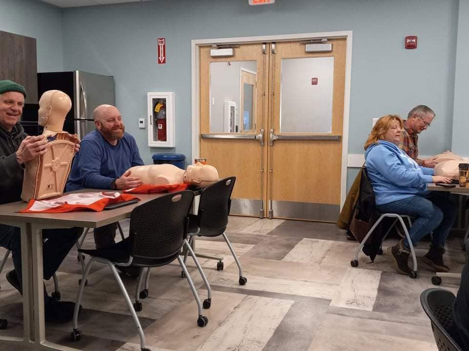 A group of people are sitting at tables in a room with mannequins.