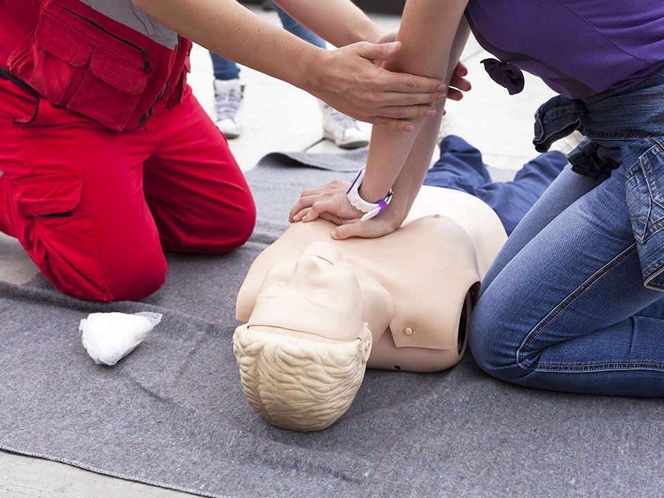 A man and a woman are doing a cpr on a mannequin.