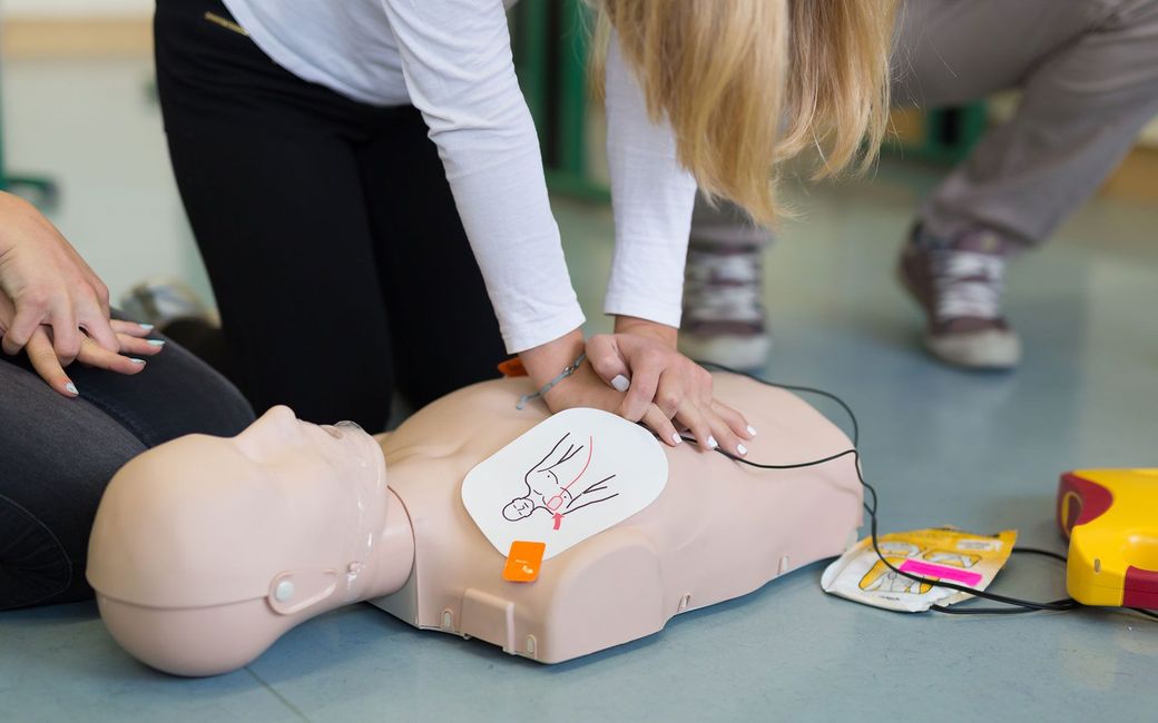 A woman is doing a cpr on a mannequin.