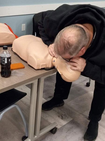 A man is practicing on a mannequin with a bottle of coke next to him