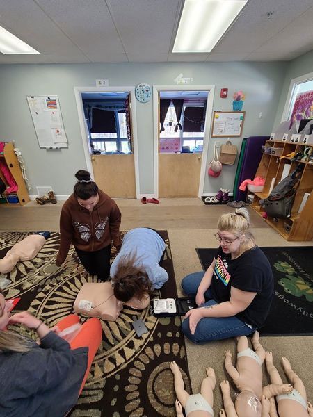 A group of people are sitting on the floor in a room with mannequins.